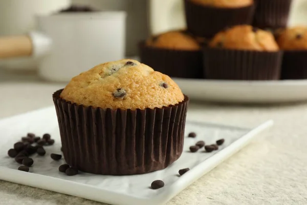 Delicious sweet muffin with chocolate chips on light textured table, closeup. Space for text