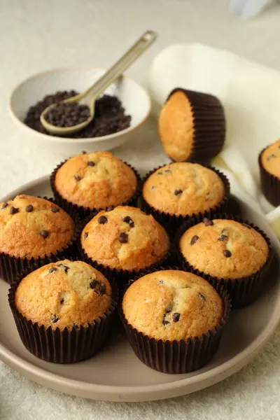 Delicious sweet muffins with chocolate chips on light textured table