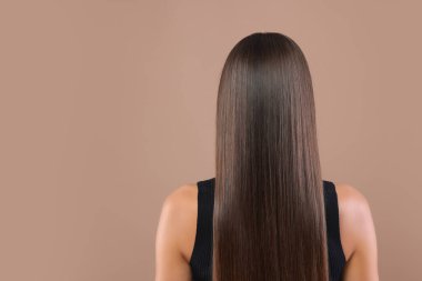 Saç şekillendirme. Düz, uzun saçlı, soluk kahverengi arka planda bir kadın. Metin için boşluk