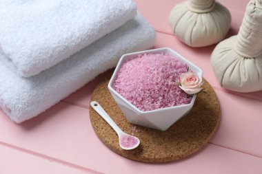 Pembe ahşap masa üzerinde deniz tuzu ve bitkisel poşetlerle kompozisyon