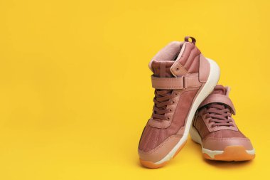 Sarı arka planda bir çift şık çocuk ayakkabısı. Metin için boşluk