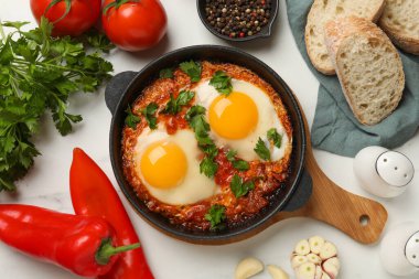 Lezzetli Shakshuka ile bembeyaz masada tavada düz bir kompozisyon.