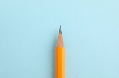 Açık mavi arkaplanda keskin bir grafit kalem, üst görünüm