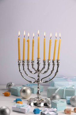 Hanuka kutlaması. Mum yakan Menorah. Dreidels, hediye kutuları ve beyaz ahşap masa üzerindeki tatil süsleri.