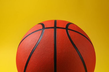 Sarı arka planda yeni bir basketbol topu, yakın plan.