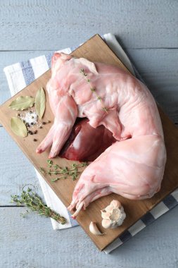 Gri ahşap masada tam çiğ tavşan, ciğer ve baharatlar, üst manzara.