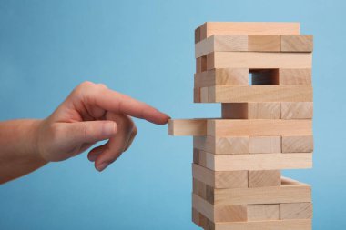 Açık mavi arka planda Jenga oynayan kadın, yakın plan