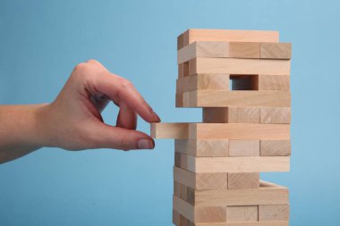 Açık mavi arka planda Jenga oynayan kadın, yakın plan