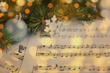 Noel ve Yeni Yıl müziği. Firavun ağacı dalı ve müzik sayfalarındaki şenlik dekoru, bokeh etkisi