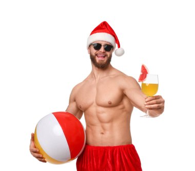 Beyaz arka planda top ve kokteyl ile Noel Baba şapkalı kaslı genç adam.