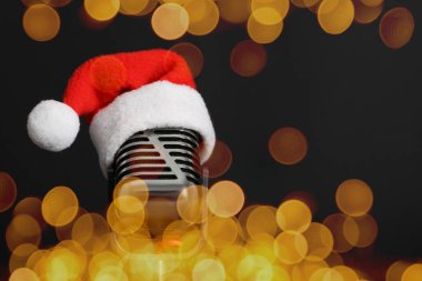 Noel müziği. Siyah arka planda Noel Baba şapkası olan mikrofon, bokeh etkisi