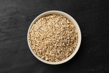 Koyu gri masada kasede kuru inci arpa, üst manzara.