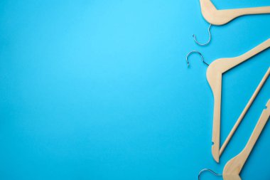 Açık mavi arka planda ahşap askılar, düz yatış. Metin için boşluk