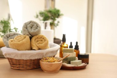 Kuru çiçekler, sabun barları, gerekli yağlar, içinde krema ve havlu bulunan kavanozlar ahşap masa içinde, yazı için yer. Spa zamanı