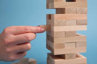 Açık mavi arka planda Jenga oynayan kadın, yakın plan