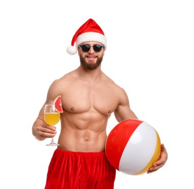 Beyaz arka planda top ve kokteyl ile Noel Baba şapkalı kaslı genç adam.