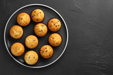 Koyu gri masa üzerinde çikolata parçacıklı taze pişmiş kekler. Metin için boşluk