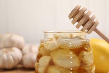 Cam kavanozda sarımsaklı bal ve bulanık arka planda kırmızı şarap, yakın plan. Metin için boşluk