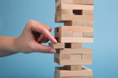 Açık mavi arka planda Jenga oynayan kadın, yakın plan