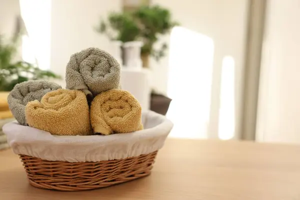 Basket with towels on wooden table indoors, space for text. Spa time