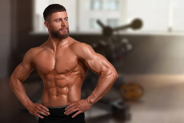Handsome bodybuilder with muscular body in gym, space for text