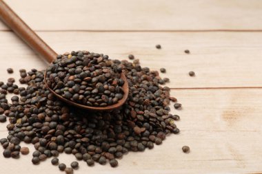 Kaşık ve açık ahşap masada bir sürü çiğ mercimek, yakın plan. Metin için boşluk