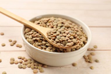 Çiğ mercimek kasede ve kaşık açık tahta masada, yakın plan.