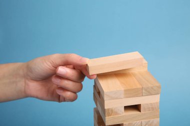 Açık mavi arka planda Jenga oynayan kadın, yakın plan