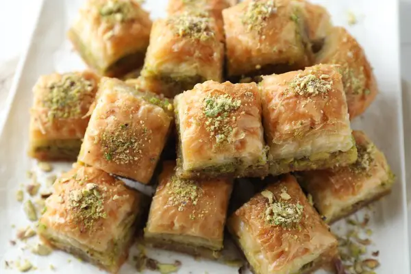 Delicious fresh baklava with chopped nuts on plate, closeup. Eastern sweets