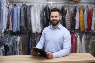 Kuru temizleme servisi. Kapalı alanda pano tutan mutlu işçi.