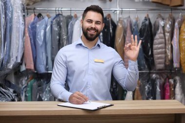 Kuru temizleme servisi. Mutlu işçi, içerideki tezgahta jest yapıyor.