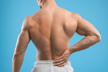 Man suffering from back pain on light blue background, closeup clipart