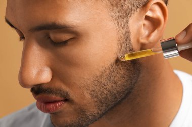 Yüzüne kozmetik serumu süren yakışıklı bir adam.