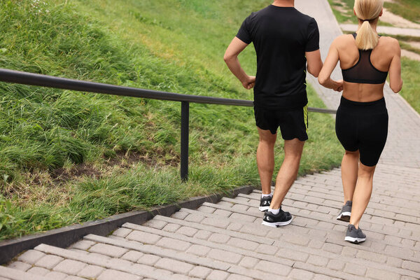 Healthy lifestyle. Couple running down stairs outdoors, back view