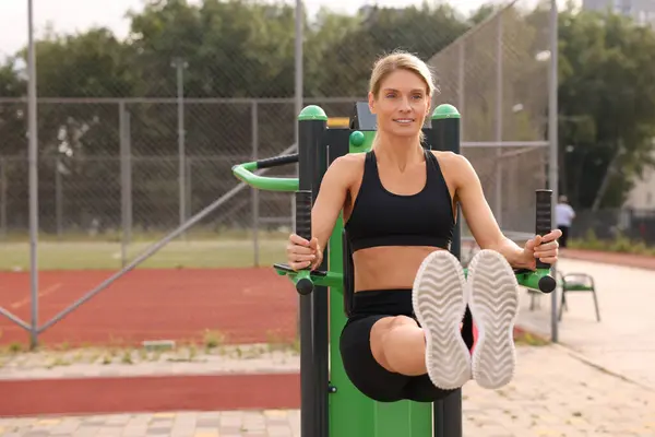 Woman training on abs station at outdoor gym, space for text