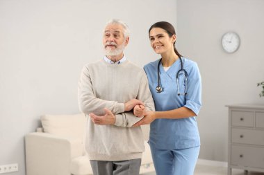 Hastanede yaşlı hastalara bakan gülümseyen hemşire.