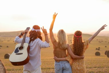 Gitarlı hippi arkadaşlar barış işaretleri gösteriyorlar.