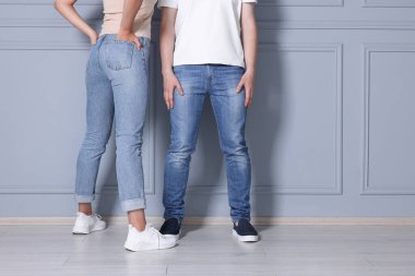 Açık gri duvarın yanındaki şık kotlu insanlar kapalı mekanda, yakın plan