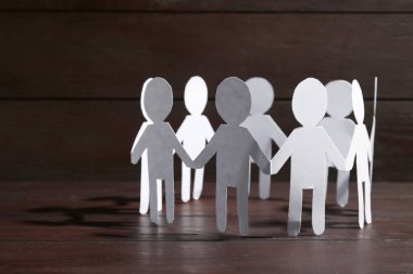 Takım çalışması konsepti. Tahta masada el ele tutuşan insanların kağıt figürleri, metin için yakın plan ve boşluk