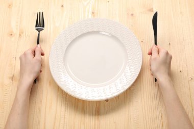 Çatallı, bıçaklı ve boş tabaklı kadın ahşap masada, yakın plan.