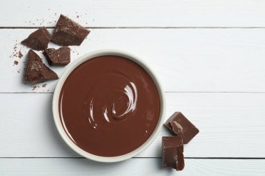 Lezzetli sütlü çikolata ezmesi kasede ve beyaz ahşap masada, düz yerde. Metin için boşluk