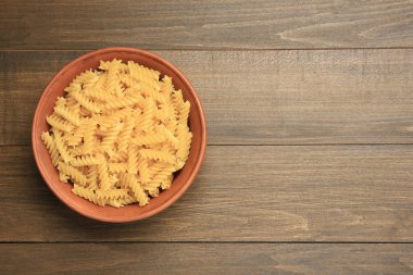 Tabakta çiğ fusilli makarna, ahşap masa, üst manzara. Metin için boşluk