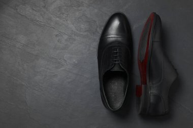 Siyah yüzeyde bir çift deri adam ayakkabısı, üst manzara. Metin için boşluk