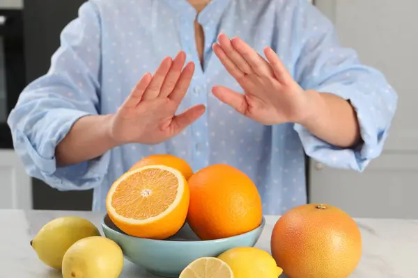 Woman suffering from food allergies refusing eat citrus fruits at table indoors, closeup