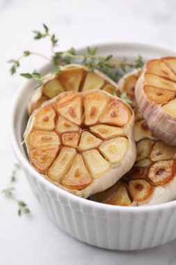 Kızarmış sarımsak ve kekik kafaları beyaz masada, yakın plan.