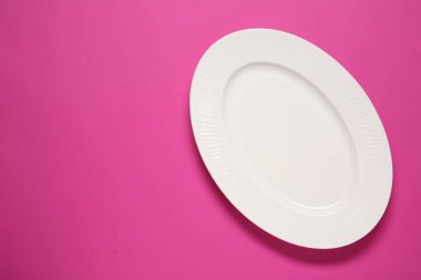 Pembe arka planda beyaz bir tabak, üst manzara. Metin için boşluk