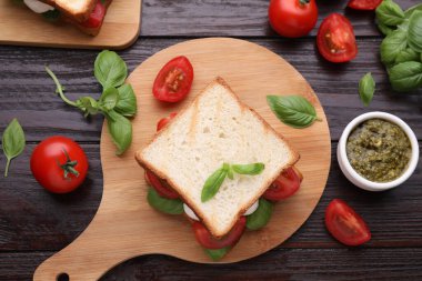 Nefis Caprese sandviçi, mozzarella, domates, fesleğen ve pesto sosu ahşap masada, düz yerde.