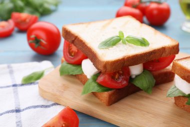 Mozarella, domates, fesleğen ve pesto soslu leziz Caprese sandviçi açık mavi ahşap masada, yakın plan. Metin için boşluk