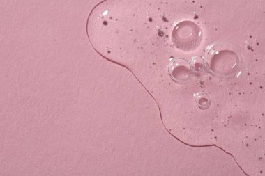 Pembe arka planda temiz kozmetik serumu, üst manzara. Metin için boşluk