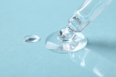 Açık mavi arkaplanda kozmetik serumlu boru, yakın plan.
